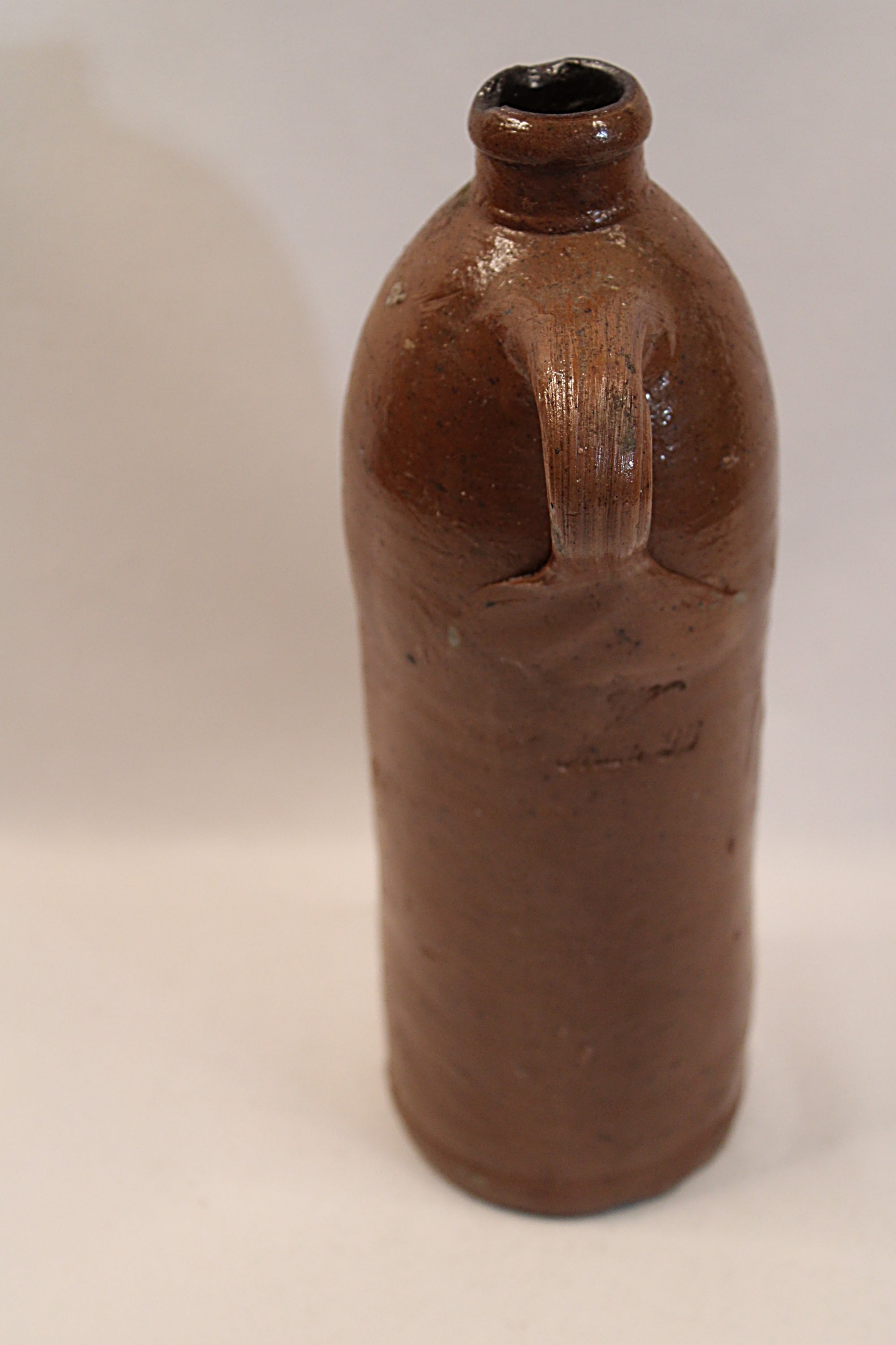 Antique ceramic bottle with a handle front on a white background