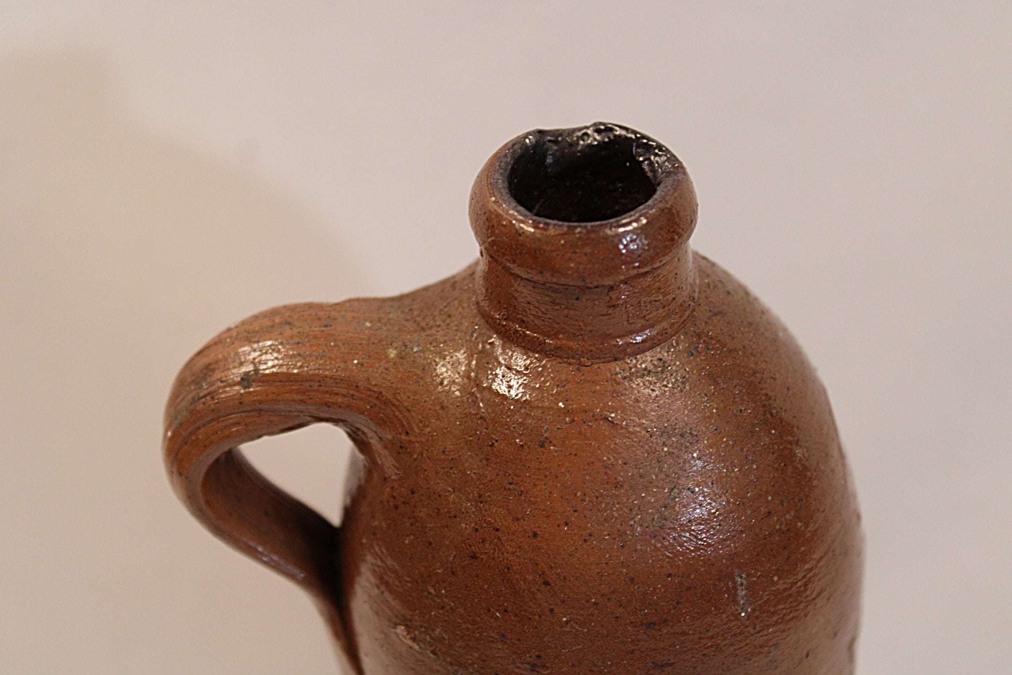 Antique Brown ceramic jug with a handle on a beige background