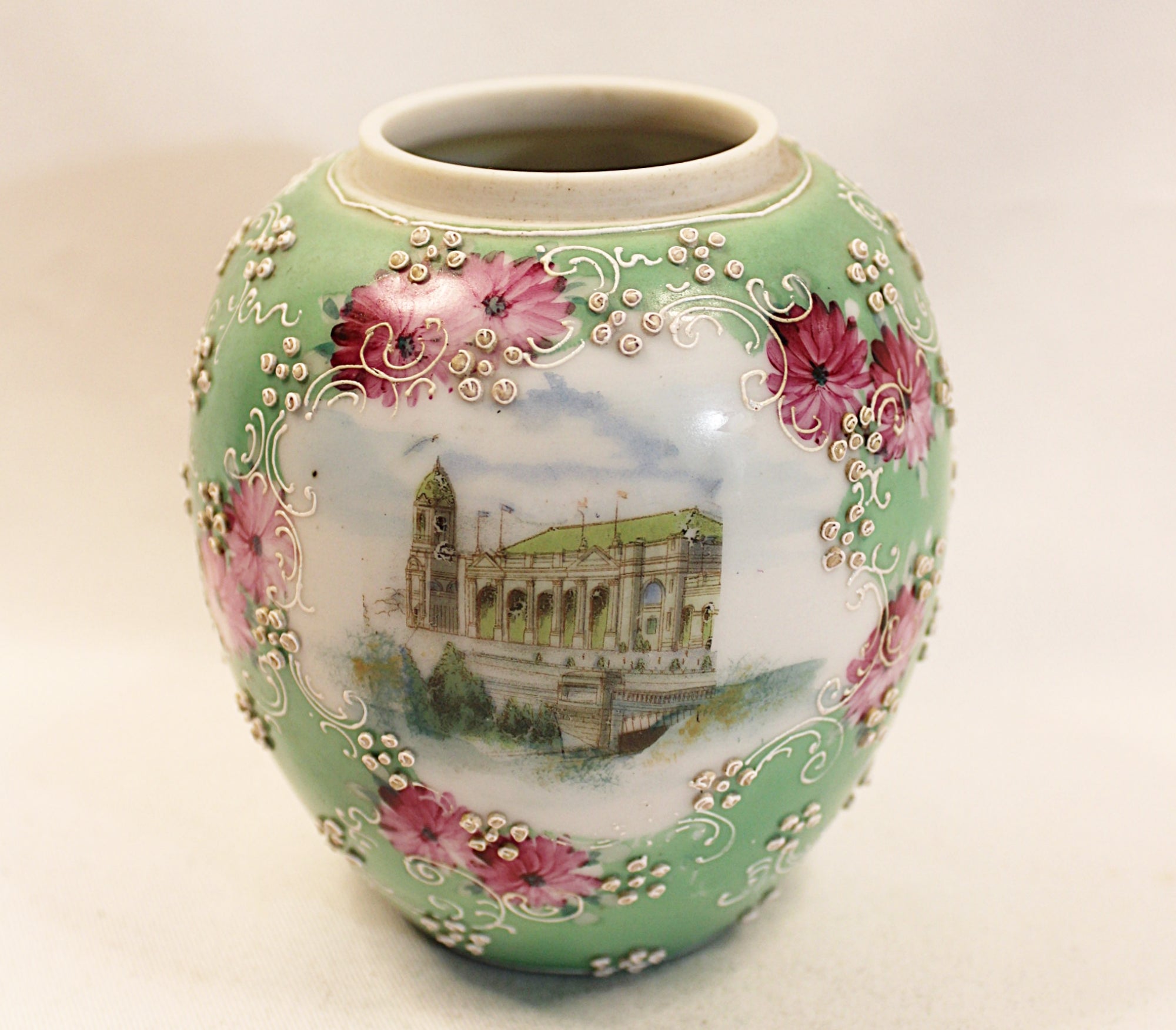Decorative ceramic vase with floral patterns and a scenic design on a plain background