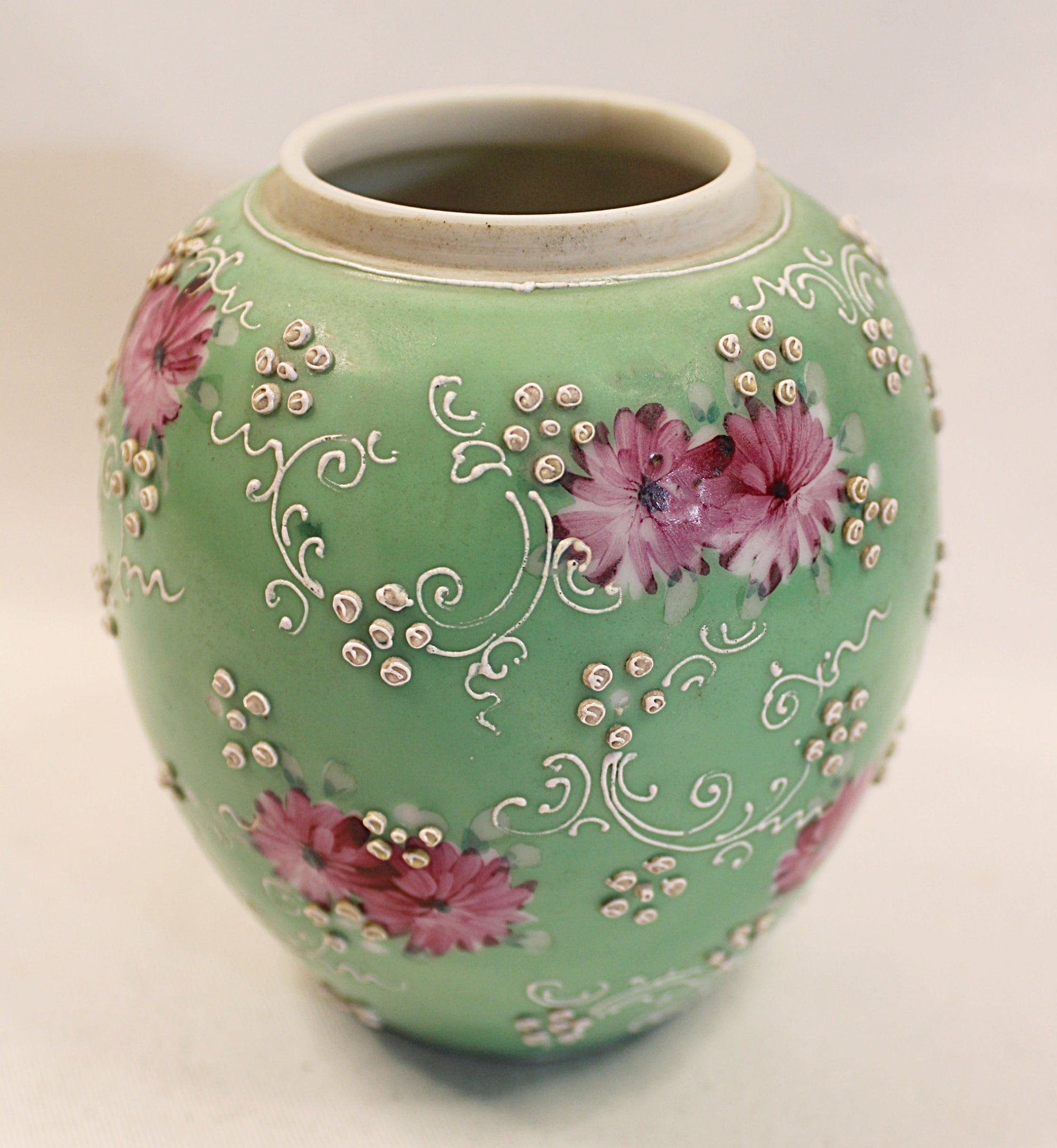 Decorative green vase with floral patterns on a light background