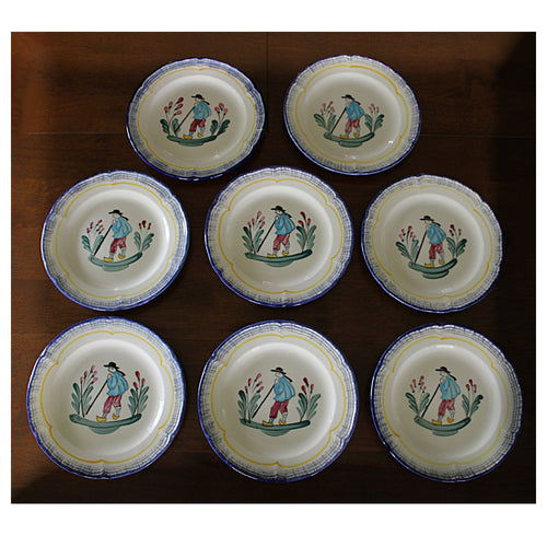 Set of eight ceramic FRENCH FAIENCE PLATES  with decorative designs on a wooden surface