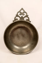 Decorative metal dish with intricate handle on a white background