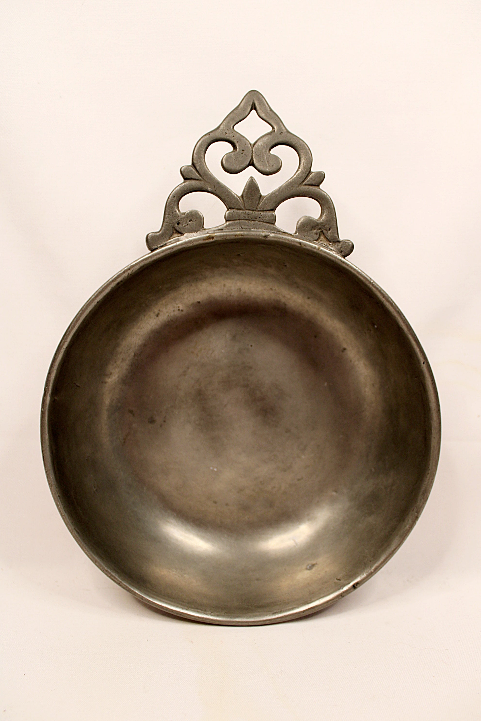Decorative metal dish with intricate handle on a white background