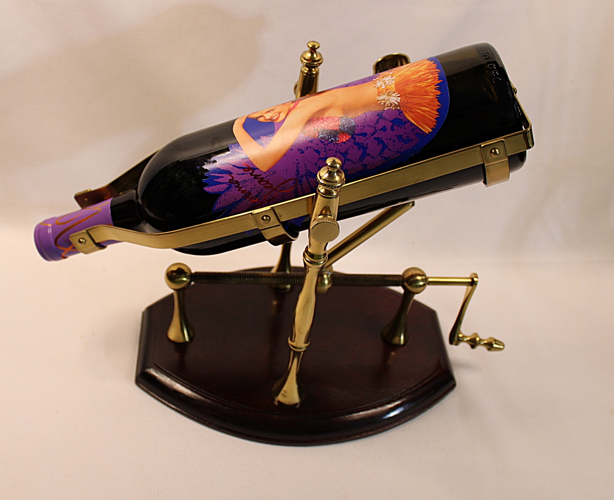 Decorative wine bottle holder with a gold and walnut wood base on a white background