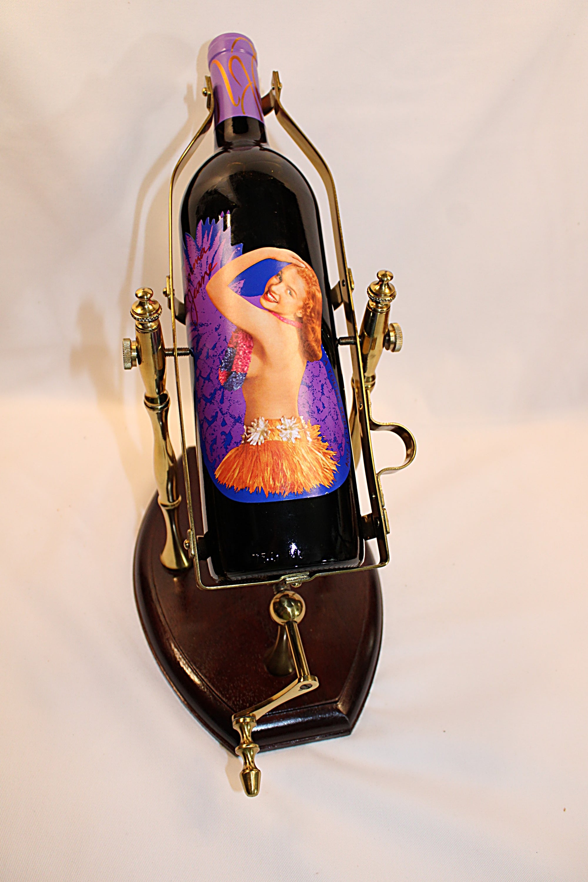 Wine bottle with artistic label in a decorative holder on a white background