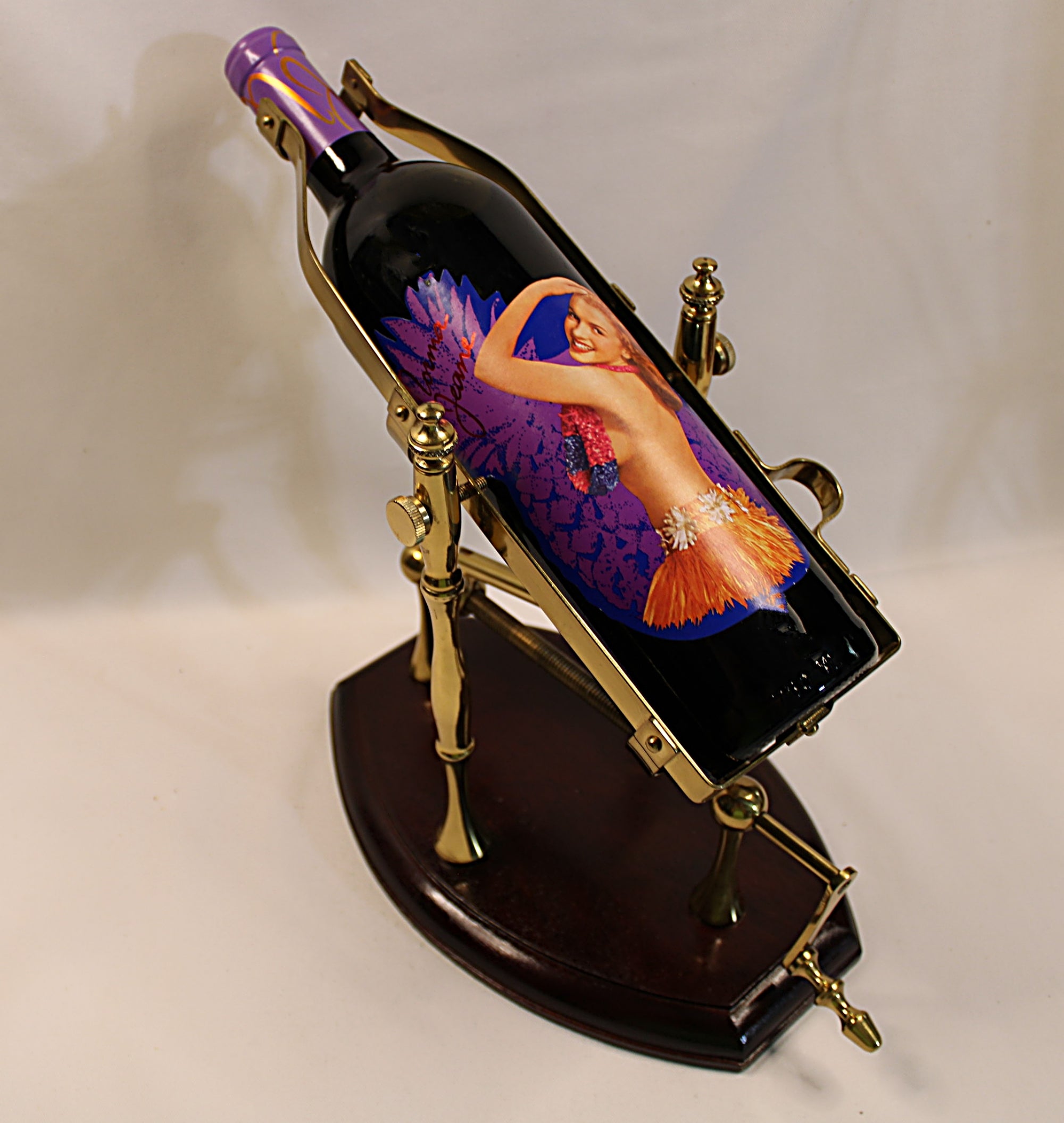 Wine bottle with artistic label of Marilyn Monroe in a decorative holder on a plain background