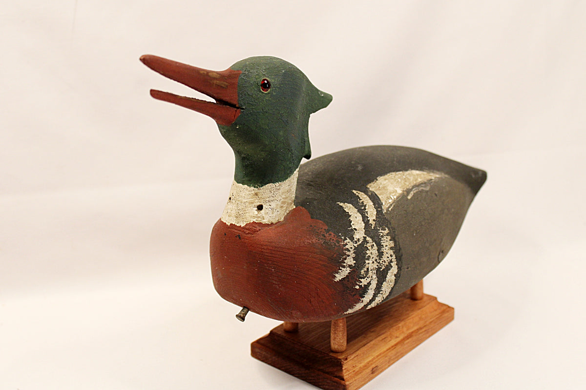Wooden duck decoy on a stand with a plain background
