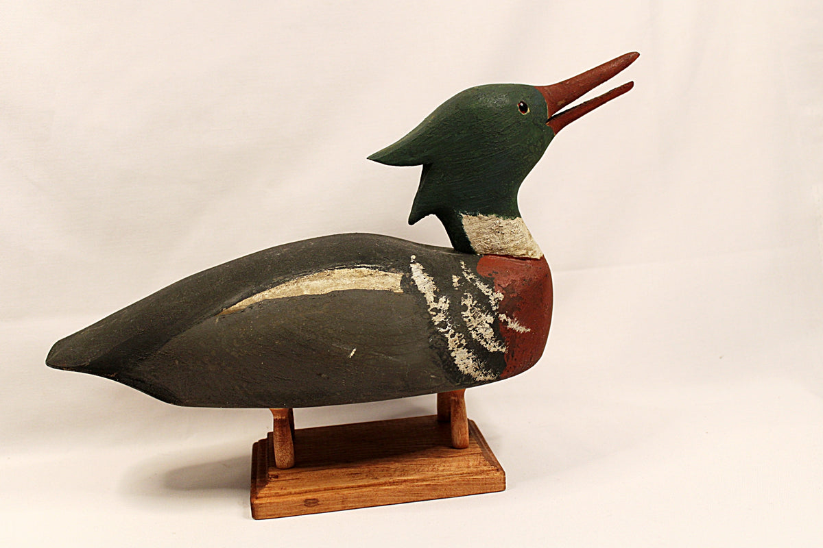 Wooden duck decoy on a stand against a plain background