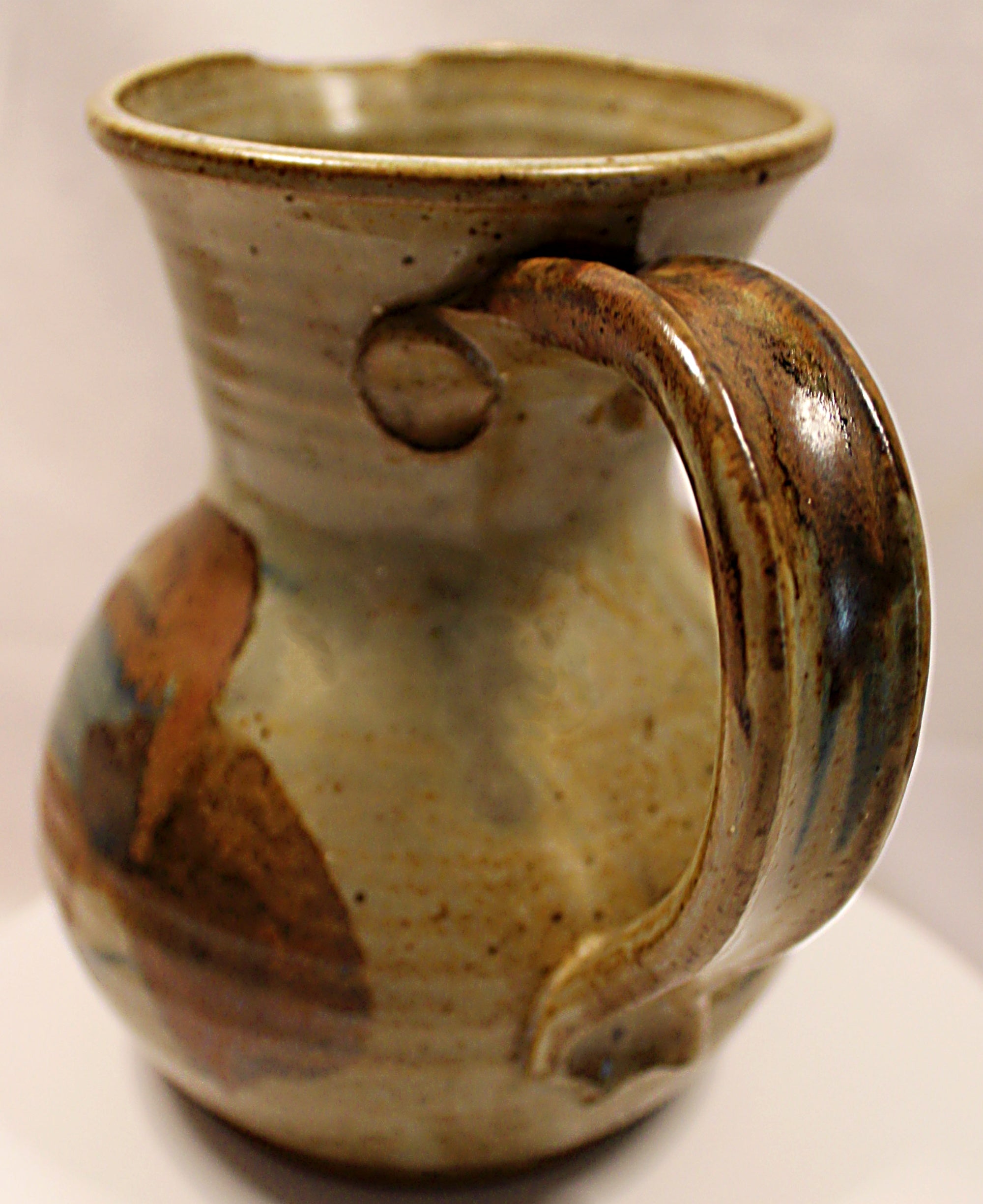 Stoneware mug with brown and beige glaze on a white background Handle-closeup-by Bill Heyduck