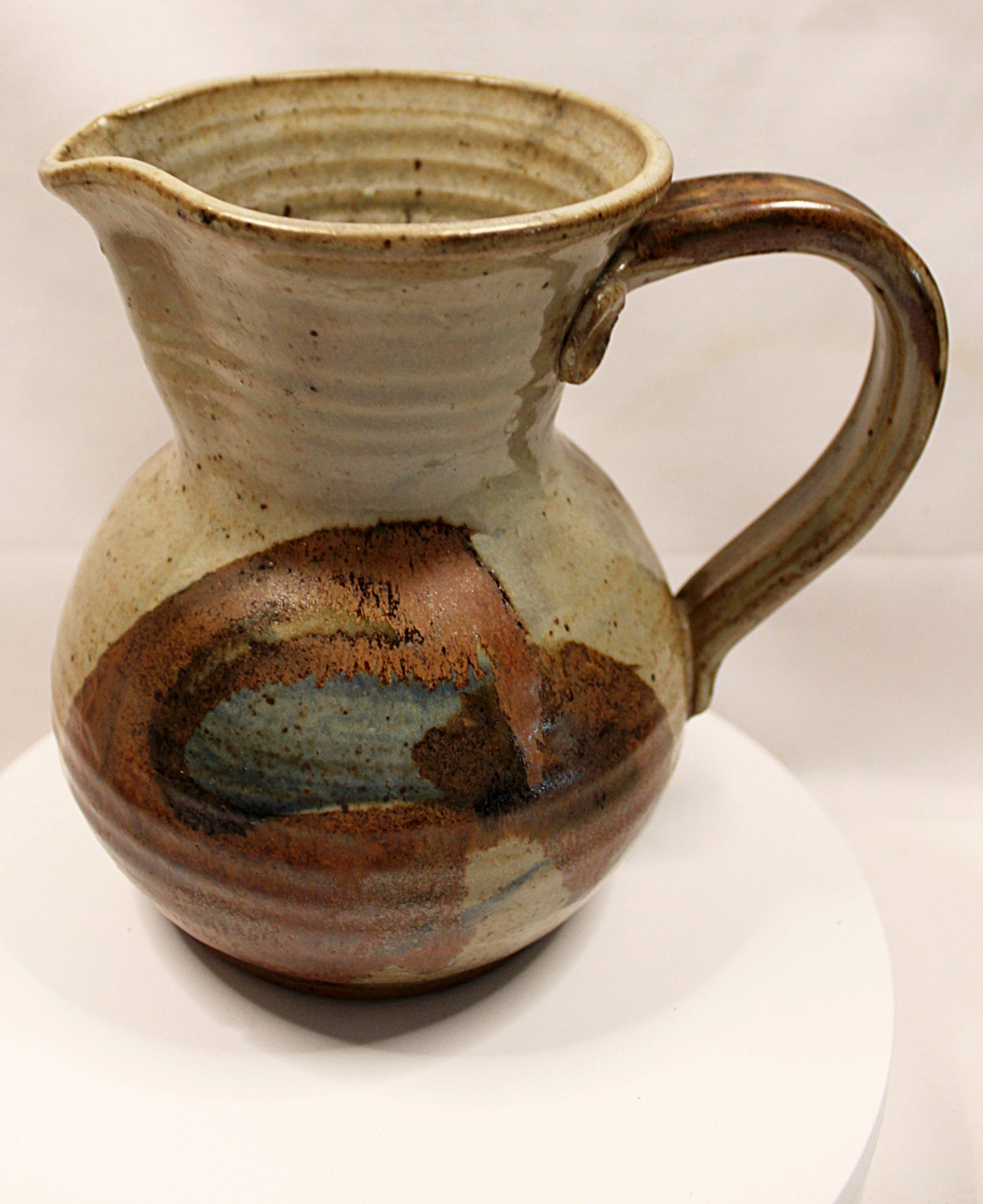 Stoneware pitcher with brown and blue glaze on a white background handle right side by Bill Heyduck