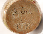 Close-up of a ceramic item with a signature and date on a white  signed Heyduck 1993background