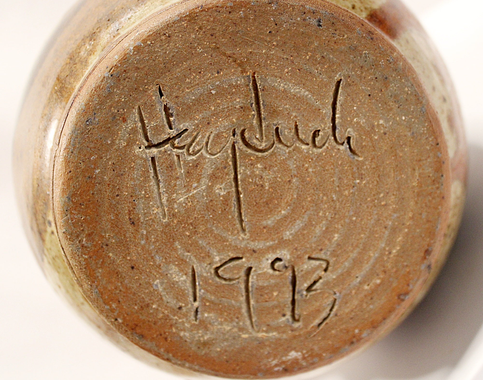 Close-up of a ceramic item with a signature and date on a white  signed Heyduck 1993background