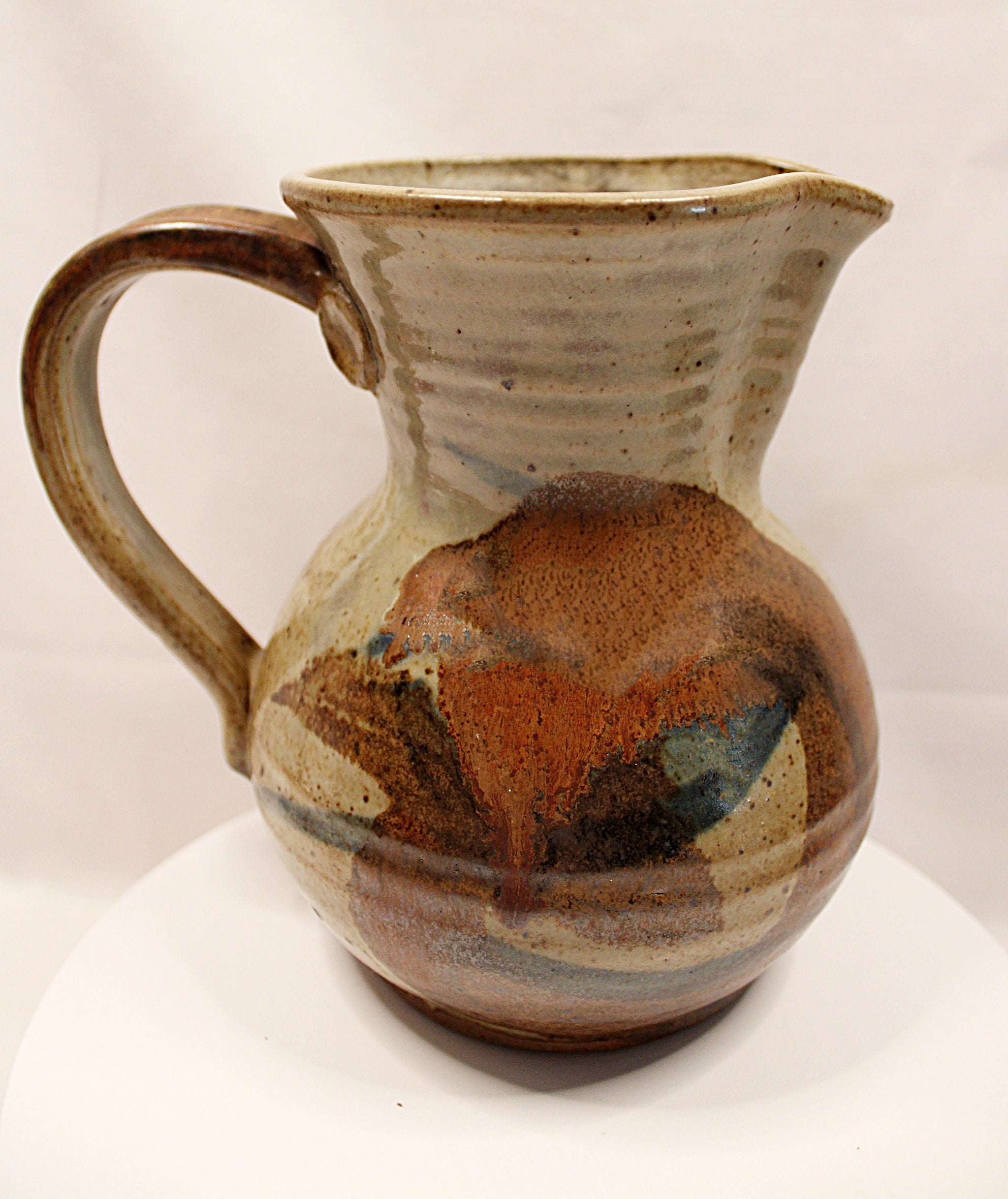 Ceramic pitcher with multicolored glaze on a white background by Bll Hyduck
