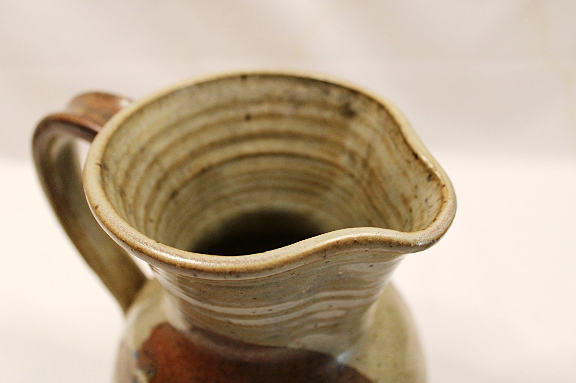 Close-up of a ceramic pitcher with a handle on a light background Rim View-by Bill Heyduck