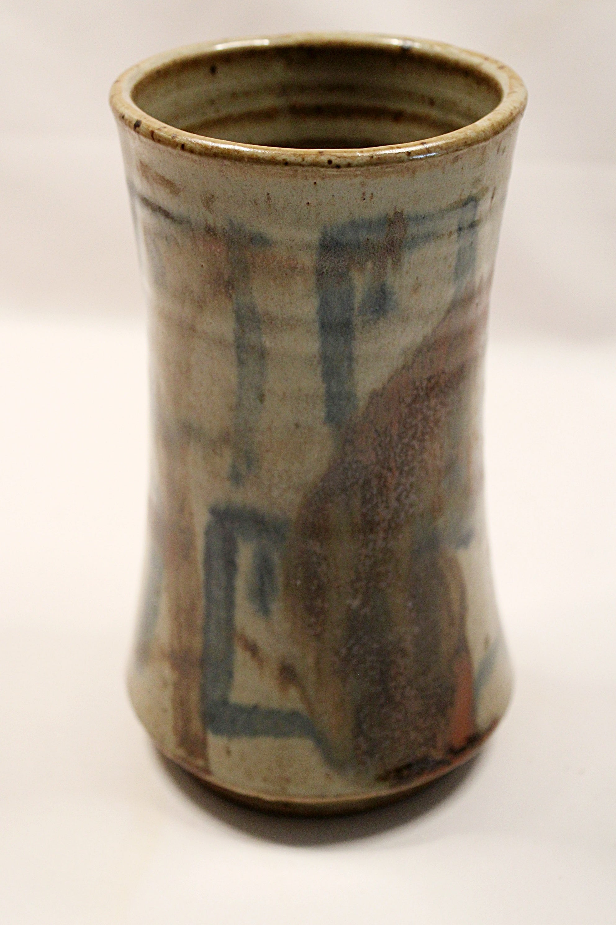 Cylindrical ceramic vase with textured surface and blue accents on a white background by Bill Heyduck