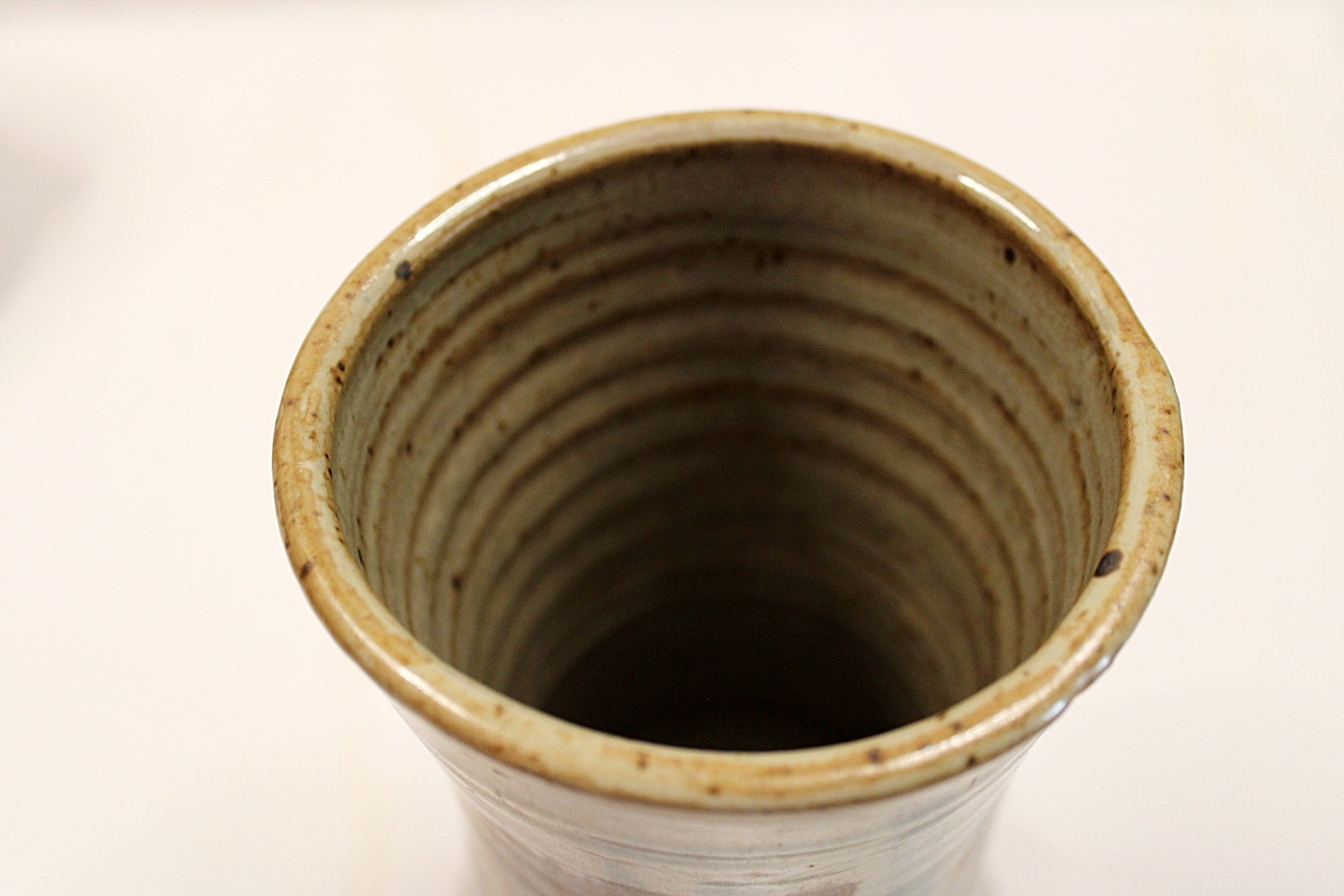 Close-up of a Bill Heyduck-ceramic vase with a textured interior on a white background