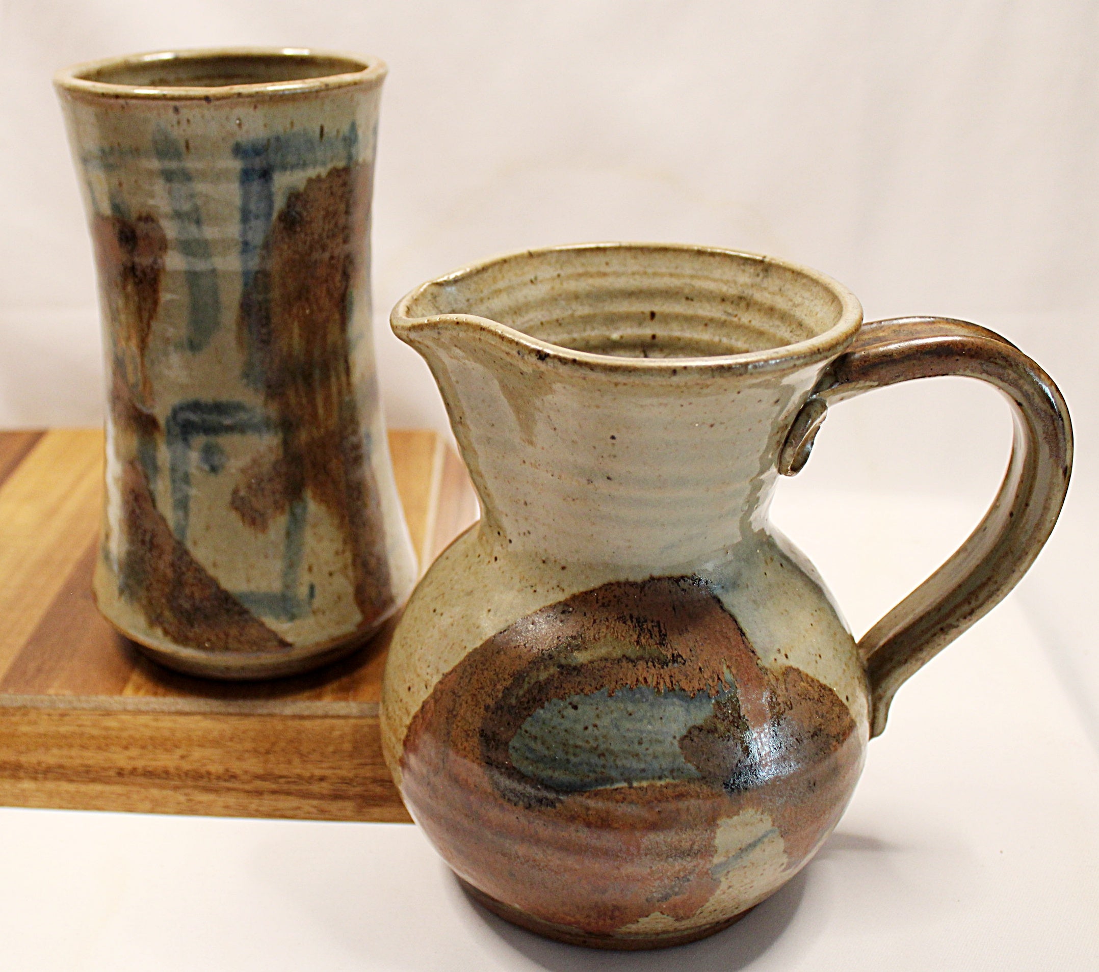 Stonewear vase and pitcher by bill heyduck in 1993 vase sitting on wood tray with white background