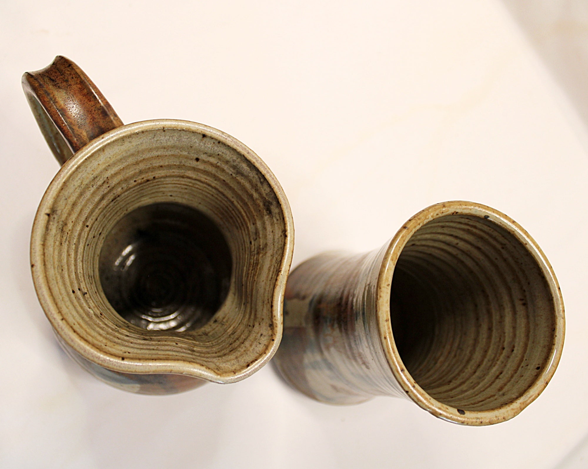 Two ceramic mugs with textured interior surfaces on a white background showing rim view of both. By Bill Heyduck potter.