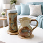 Bill Hyduck stonewear pitcher and vase on coffee table in livingroom with blue couch in background.