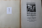 Open vintage book showing the left page with a small white label and the right page with black printed cover text reading 'CHARLES-BRUN' and 'INTERIEURS RUSTIQUES' by Charles-Moiseau.