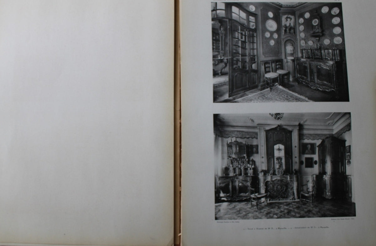 Antique French Folio Book Titled Interieurs Rustiques Paris 1926
An open vintage book or album showing an aged blank left page and a right page with two black-and-white photographs of an ornate interior room with mirrors, cabinets, and decorative wall elements.
