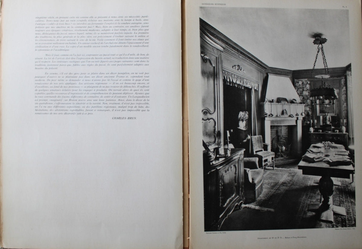 Antique French Folio Book Titled Interieurs Rustiques Paris 1926
showing a two-page spread. The left page contains printed text, and the right page features a black-and-white photograph of an ornate interior room with a fireplace, table, and hanging lamp.