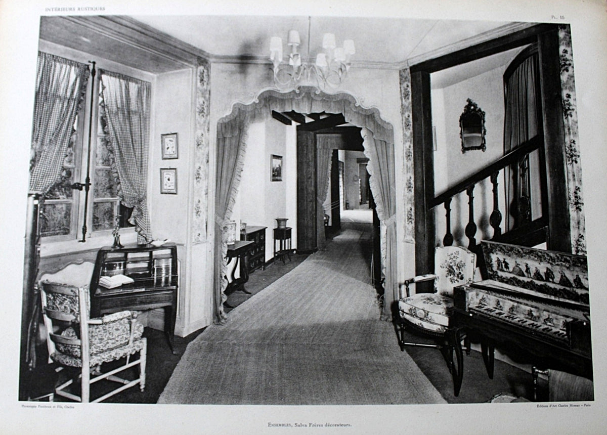 Antique French Folio Book Titled Interieurs Rustiques Paris 1926
A black and white vintage photograph print depicting an elegant interior hallway with an arched doorway, patterned curtains, a chandelier, a piano, and a staircase.