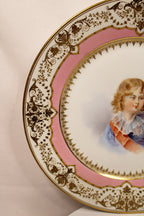 Decorative plate with a portrait of a child on a pink background left rim closeup