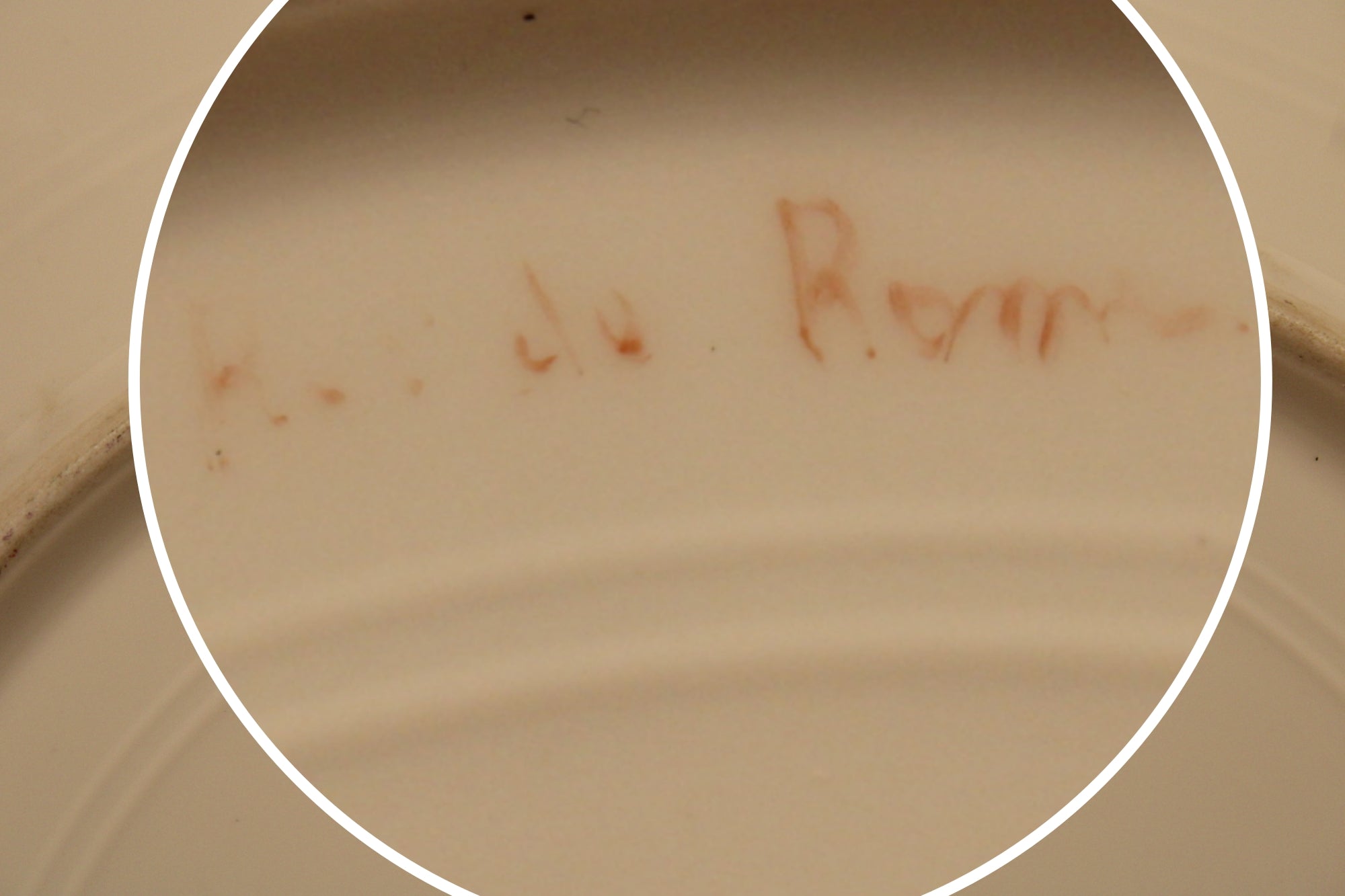 Close-up of a ceramic plate with 'R. de Rochemont' inscription.