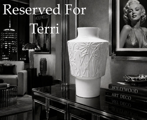 White vase on a table with 'Reserved For Terri' text in an elegant room setting.