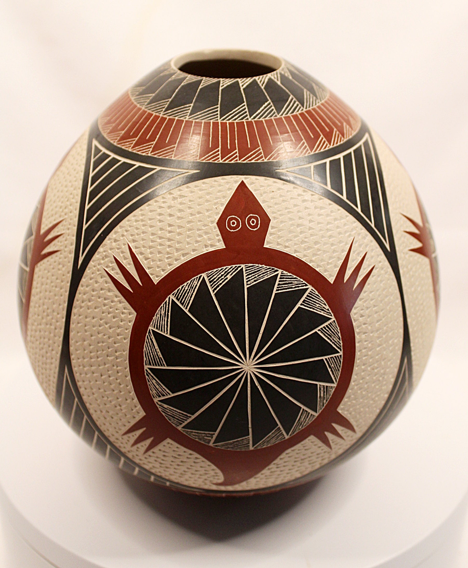 A hand-painted Southwestern-style ceramic vase with a rounded body, featuring a prominent red turtle design with a black wheel motif on an off-white textured background, with red, black, and white geometric patterns on the neck and sides.