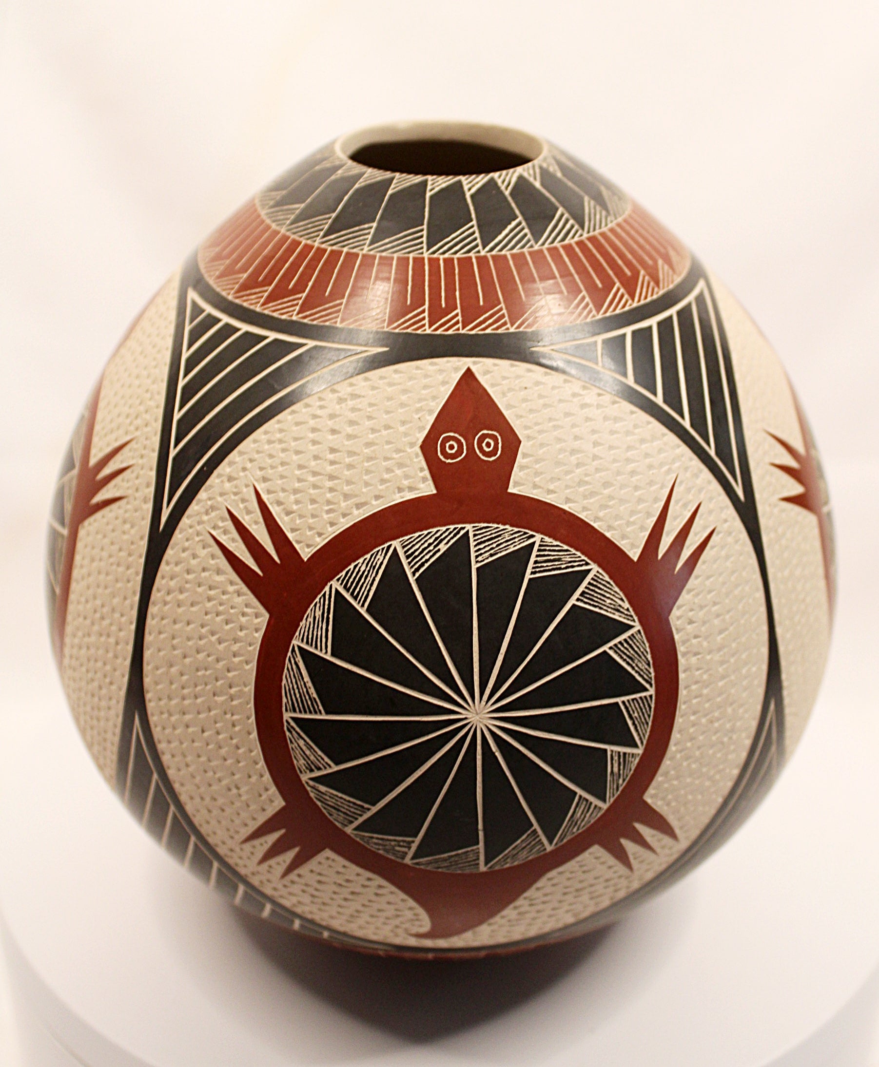 A hand-painted Southwestern-style ceramic vase with a textured cream base, featuring geometric patterns and a prominent red and black turtle design on the front, displayed on a white surface against a white background.