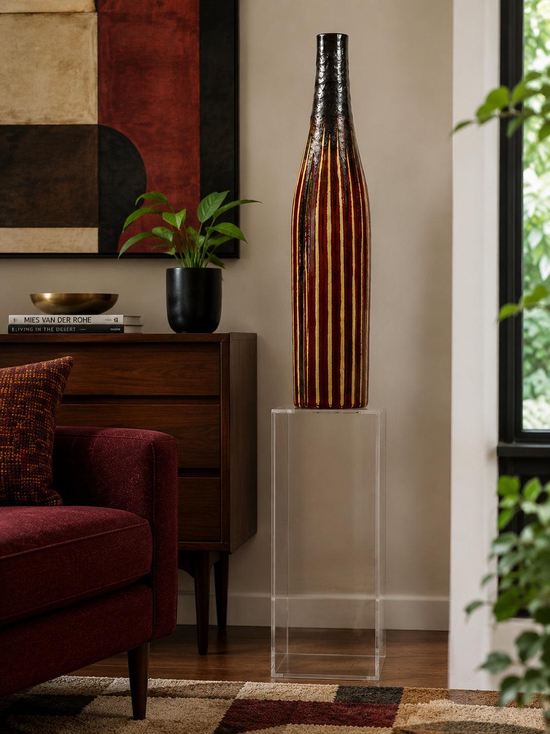 Tessuto Tall decorative vase on a clear pedestal in a living room setting with a couch and artwork.