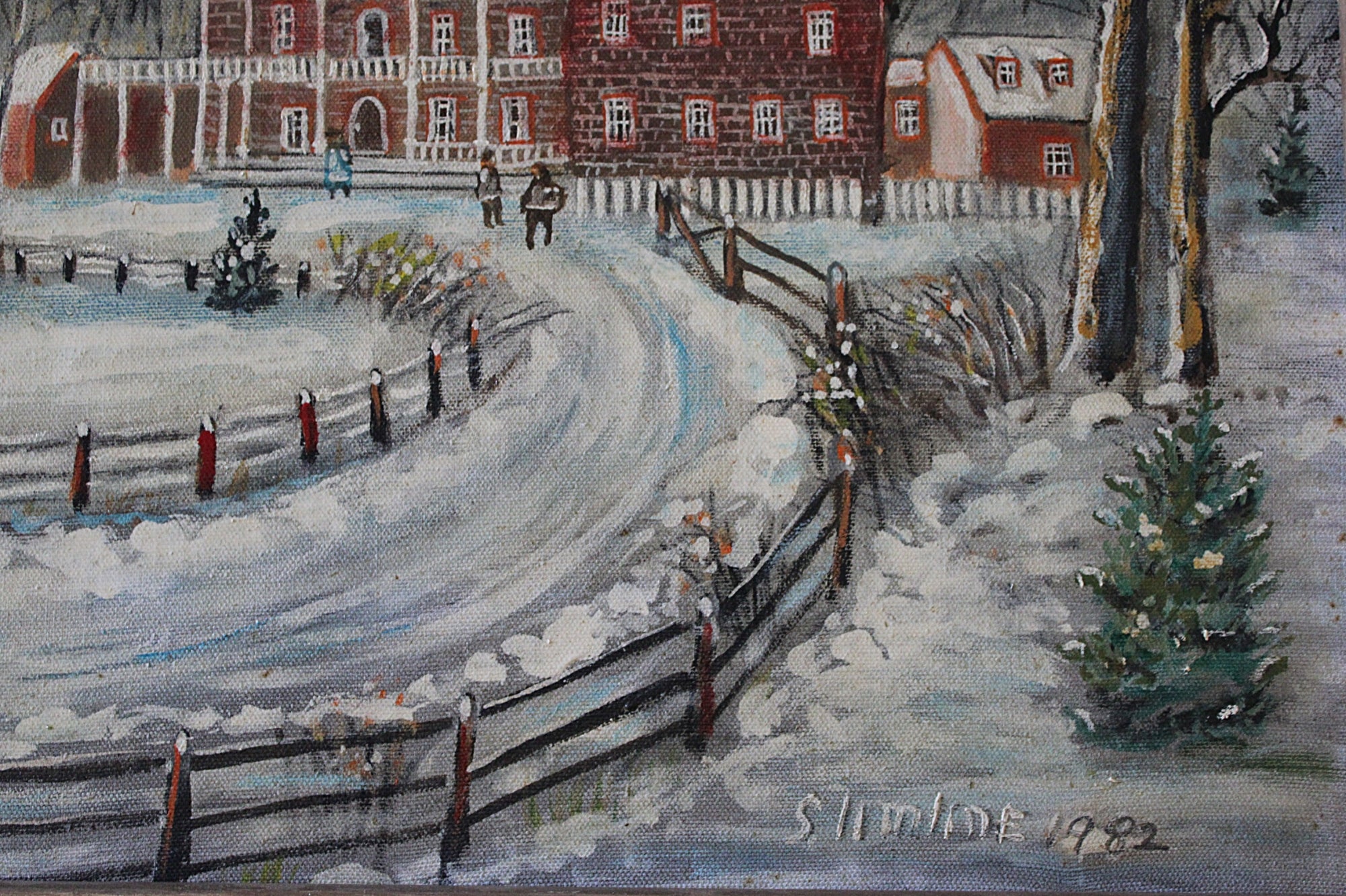 A painted winter landscape showing a snowy curved path leading toward red brick buildings, with fences, trees, and small figures in the distance. The artwork appears to be signed and dated in the lower right corner.