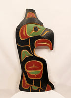 A hand-carved wooden totem pole sculpture featuring traditional Indigenous Pacific Northwest design elements in black, red, green, and gold, displayed against a plain white background.