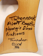 A close-up of a light natural wood plaque or sign with handwritten black marker text reading 'T.Whonnock Alert BayBc Namgis First Nations Thunder Bird'.