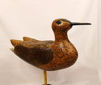 Wooden bird decoy on a stand against a plain background close up view