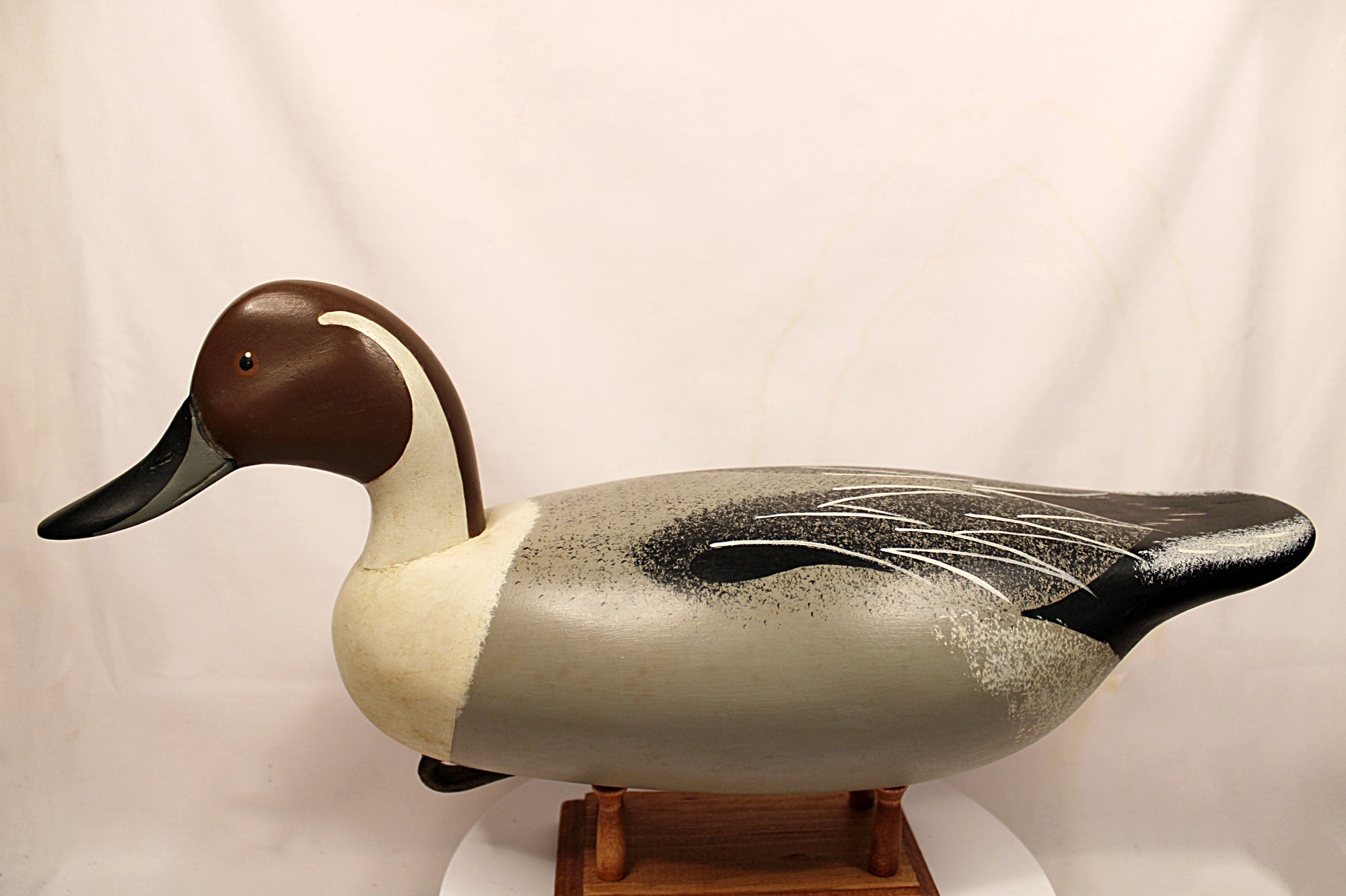 Duck decoy on a stand against a plain background Full Body Facing Left