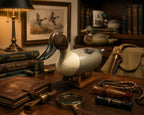 Duck decoy on a wooden table with books, a lamp, and other hunting-related items. Pintail Drake Duck Decoy Jim Burtis Maryland 1994